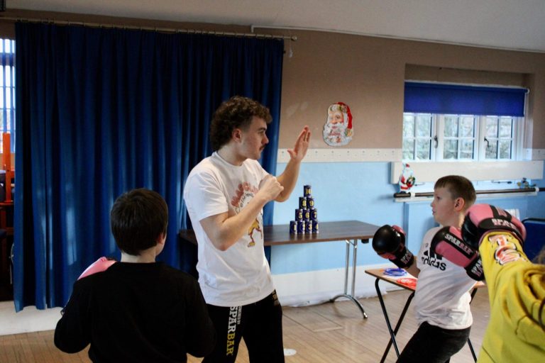 A group of young people engaged in a workshop, with a presenter speaking in front.