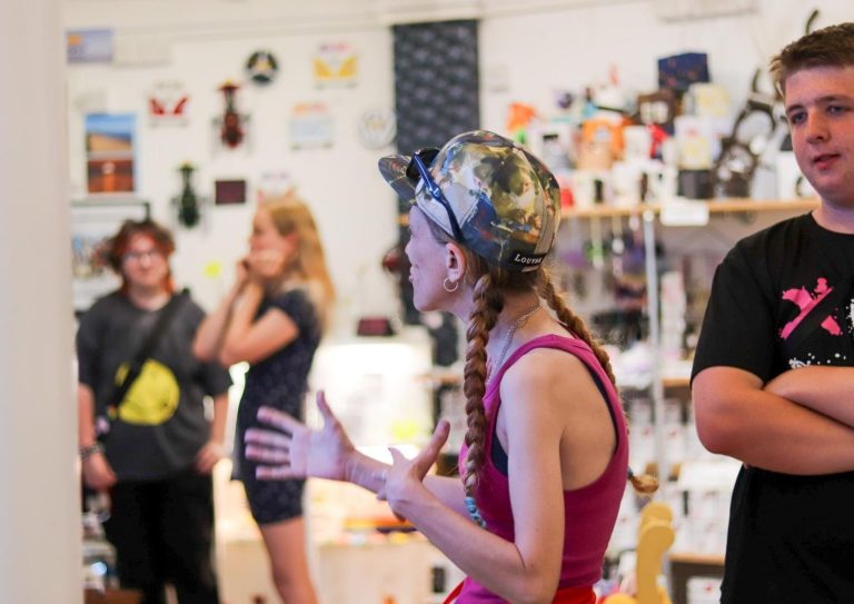 A group of people in an art space, with one person passionately speaking.