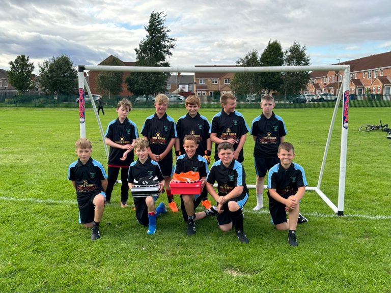 Grant Thorold JFC Boys' football team posing together in front of a goal on a grassy field.